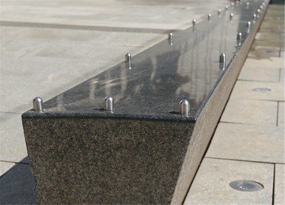 En blankpolert avlang stein er plassert som en skulptur på det romslige fortauet utenfor kontorbygningen i Haakon VIIs gate 10 i Oslo. For å hindre skating er det montert metallknotter på overflaten.