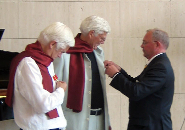 Fylkesmann i Oslo og Akershus, Hans J. Røsjorde (t.h.) fester Kongens gull til Are Teljes jakkeslag. Fredrik A.S. Torp tar sin medalje i nærmere øyensyn.