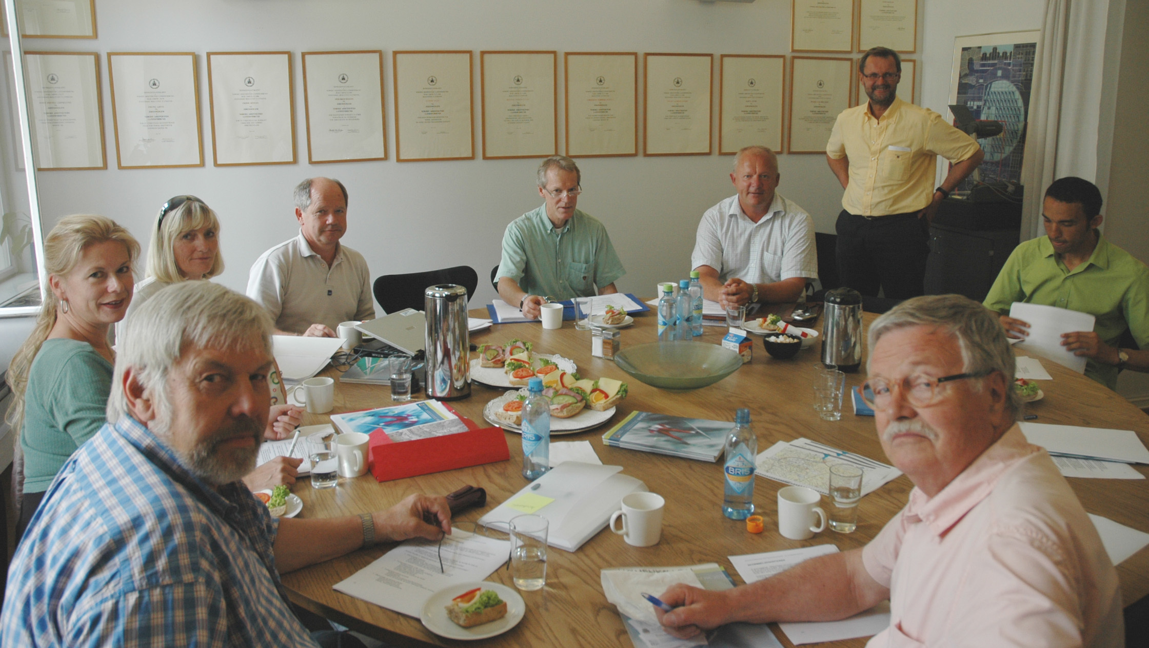 Juryen i Holmenkollkonkurransen kan snart ta fått på bunken med innkomne forslag. Fra venstre og rundt møtebordet med klokka: Trygve Sundt, landskapsarkitekt MNLA, Birgitte Riegels Høyland, landskapsarkitekt MNLA/Plan- og bygningsetaten, Bente Lill Romøren, Norges Skiforbund, Roar Gaustad, Norges Skiforbund, Steinar Helgesen, prosjektleder i kultur- og idrettsetaten, Oslo kommune (ikke medlem i juryen), Steinar Eidaker, Skiforeningen, juryleder Gary Bates, sivilarkitekt, og Jan Digerud, sivilarkitekt MNAL. Bak står jurysekretær Per Rygh. Foto: Anne Plau Hoel.