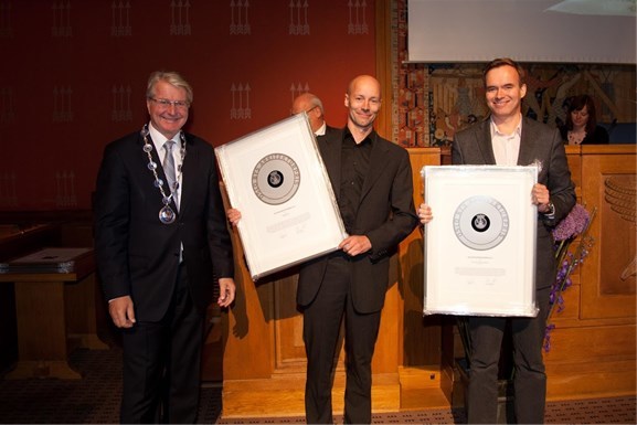 Martin Dietrichson fra KIMA arkitektur (i midten) og Kurt Singstad fra MAD (til høyre), mottar prisen fra Oslos ordfører Fabian Stang. Foto: Sturlason