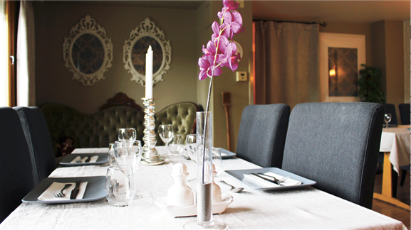 I ett av rommene er bordet alltid dekket, og alt er klart til å nyte gode måltider sammen. Med gratismøbler fra FINN og andre donasjoner har man skapt en følelse av å gå ut på restaurant. Beboerne har selv valgt ut tapetene. Foto: Hilde Helland