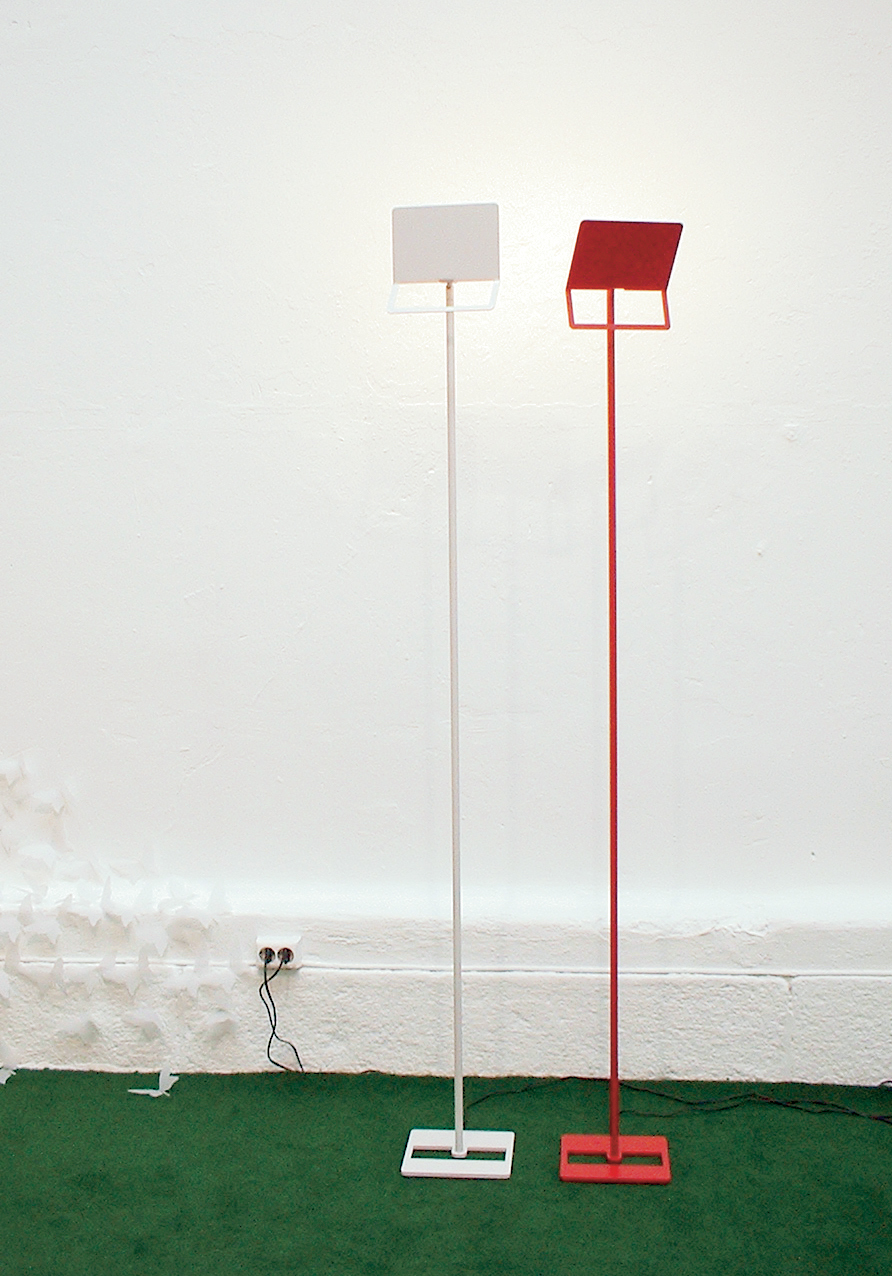 NIKK: Wallwasher gulvlampe av lakkert stål i klare farger. Enkel lik form i fot og skjerm gir et grafisk uttrykk. Lyspæren bak skjermen gir jevnt lys uten skygger fra lyskilden. En produsent er interessert i lampen. 
Design: Elling Ekornes & Trine Haddal Hovet.